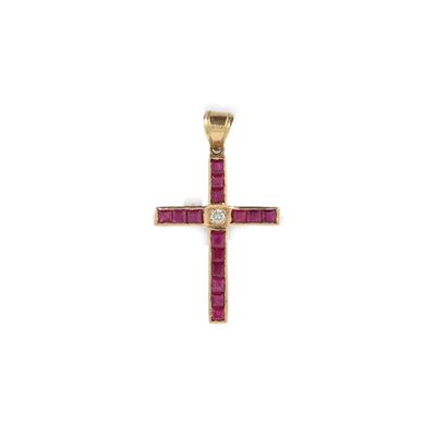 un pendentif en forme de croix en or, orné de rubis sur fond blanc