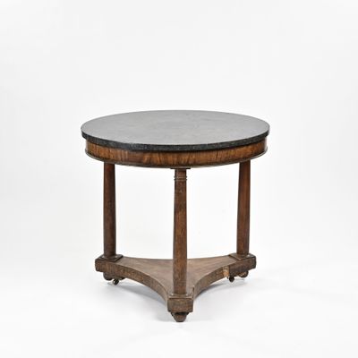 une table ronde avec un plateau en marbre noir et des pieds en bois