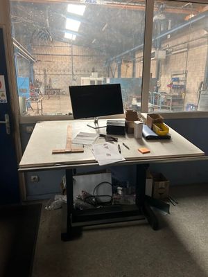 un bureau sur lequel est posé un ordinateur portable, devant une fenêtre