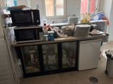 une cuisine équipée d'un réfrigérateur, d'un micro-ondes, d'un lave-vaisselle et d'autres ustensiles posés sur le plan de travail