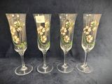 four wine glasses with flowers painted on them on a black background