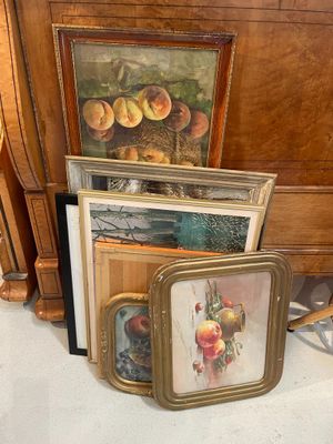 a lot of framed pictures on the floor next to a dresser
