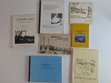 plusieurs livres posés sur un mur blanc, surmonté d'une horloge