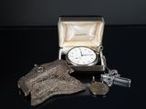 a silver clock in a silver case with a chain around it