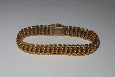 a close up of a gold bracelet on a white surface