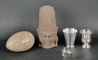 a statue of a head, a vase, and a rock on a table