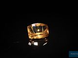 une bague en or posée sur une surface noire, avec un fond noir