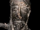 an old statue of a man with a beard holding a stick