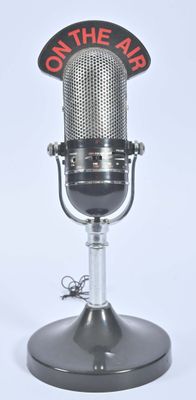 un micro à l'ancienne sur lequel est inscrit « À l'antenne »