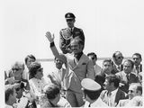 une vieille photo en noir et blanc montrant un homme en uniforme militaire faisant signe à une foule de personnes