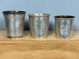 trois tasses en métal posées sur une table en bois