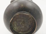 a close up of a bronze vase on a white surface