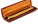 a gold bracelet in a red case on a white surface