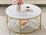 La table basse est dotée d'un plateau en verre et d'un piètement doré.