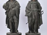 pair of bronze statues of a man and a woman dressed in period clothing