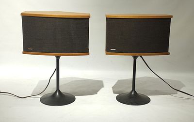 pair of speakers on stands with wires attached to them on a white surface