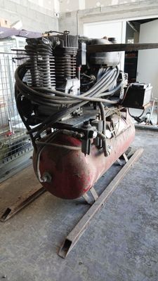 a large air compressor sitting on a stand in a room