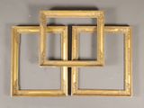 three gold picture frames on a wall with a mirror in the middle of them