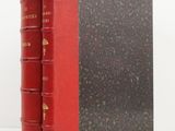 an old red book sitting on top of a table next to a white wall