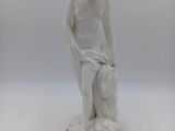 une statue blanche représentant un garçon tenant un sac, posée sur un socle en bois