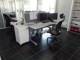 a desk with two computers and a chair in the room
