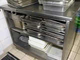 many trays of food sitting on a shelf in the kitchen