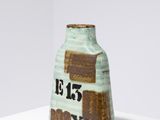 un petit vase vert orné d'un motif marron et blanc