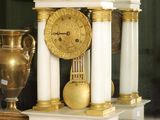 une horloge posée sur une table à côté d'un vase