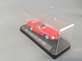 a red toy car in a clear case on a table