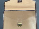 brown and tan leather briefcase sitting on top of a black table