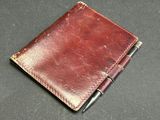 an image of a leather notebook with a pen resting on top of it