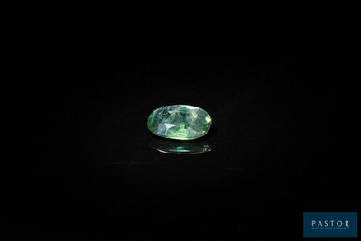 a close up of a green sapphire stone on a black surface