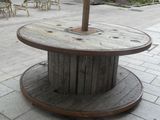 a wooden table with a umbrella on it on the sidewalk