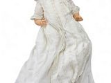 une poupée ancienne en porcelaine représentant une femme en robe blanche