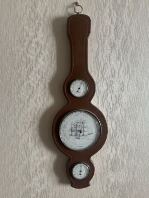 une horloge accrochée au mur, sur laquelle est fixé un baromètre