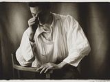 photographie en noir et blanc d'un homme assis sur une chaise, en train de parler au téléphone portable