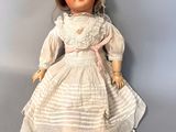 an image of a doll with a white dress and brown shoes
