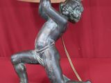 a statue of a boy holding a lamp on a table