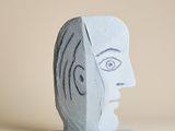 une sculpture représentant le visage d'un homme, posée sur un socle