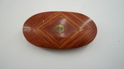 un objet en bois de forme ovale orné d'un motif en losange