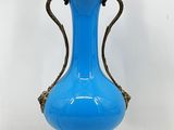 un vase bleu posé sur un socle, auquel est attachée une chaîne