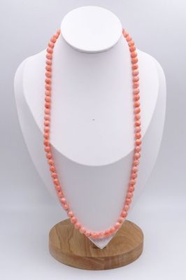 a close up of a necklace on a mannequin on a wooden stand