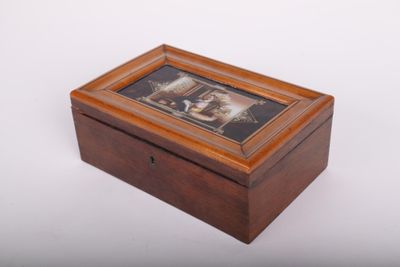 une vieille boîte en bois contenant une image posée sur une surface blanche