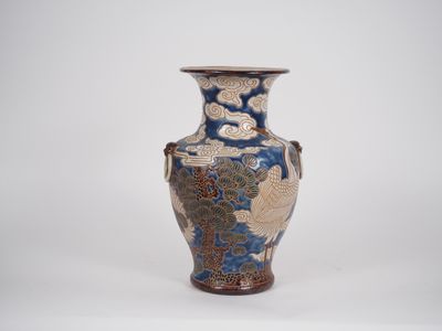 un vase bleu et or posé sur une surface blanche