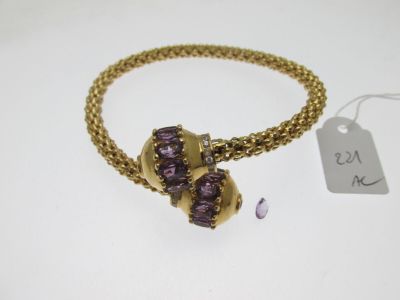 un gros plan d'un bracelet en or orné de pierres violettes