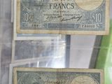 two old french bank notes on display in a glass case