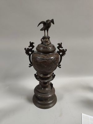 a bronze urn with a bird on top of it