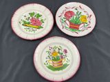 three plates with flowers on them sitting on a table