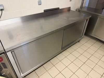 a stainless steel counter top in a kitchen with a refrigerator