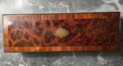 une vieille boîte en bois munie d'une poignée en métal, posée sur une surface en marbre